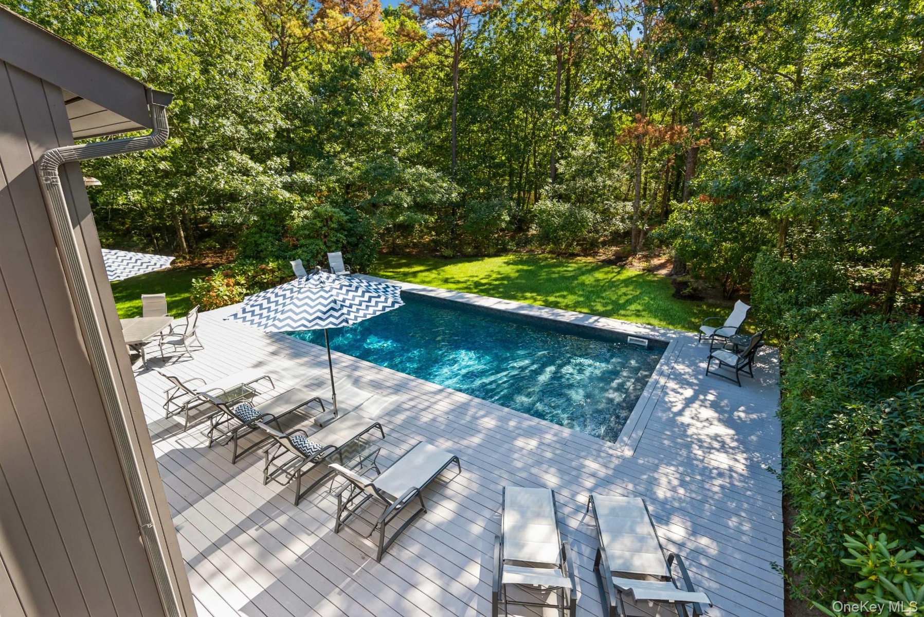 Outdoor pool with a wooden deck, a lawn, and outdoor dining space