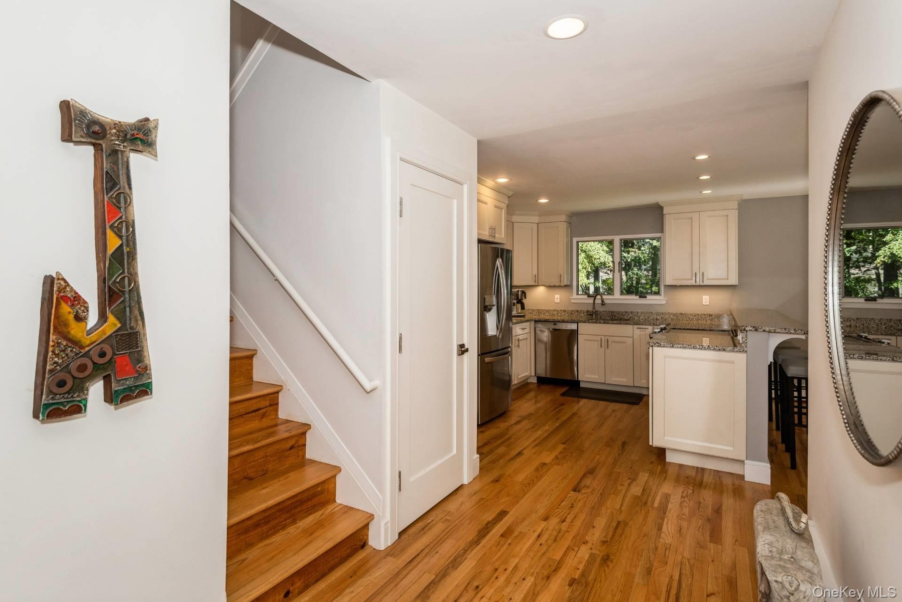 Kitchen with recessed lighting, dark wood-type flooring, light stone countertops, a peninsula, and appliances with stainless steel finishes