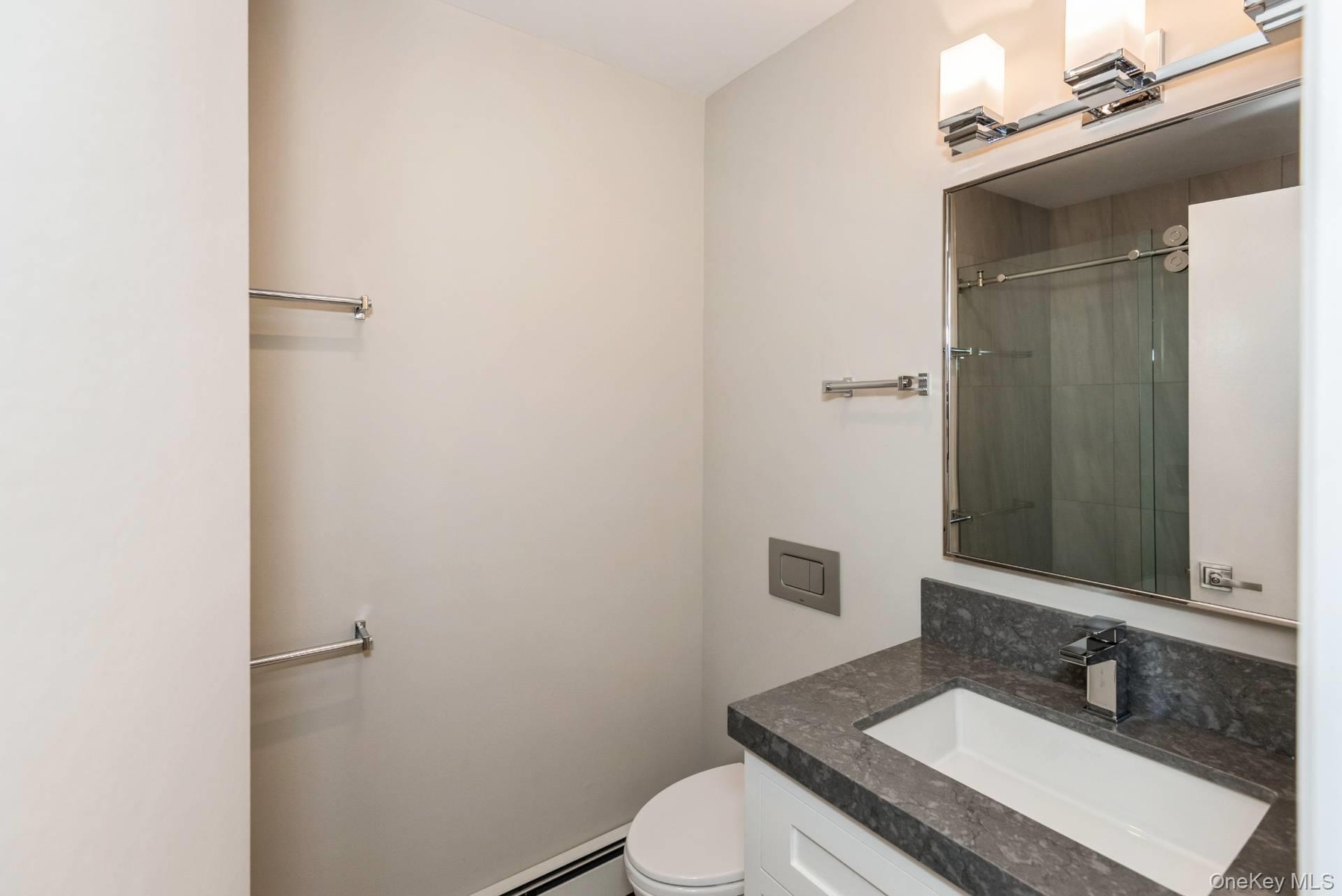 Bathroom with vanity, baseboard heating, and a tile shower