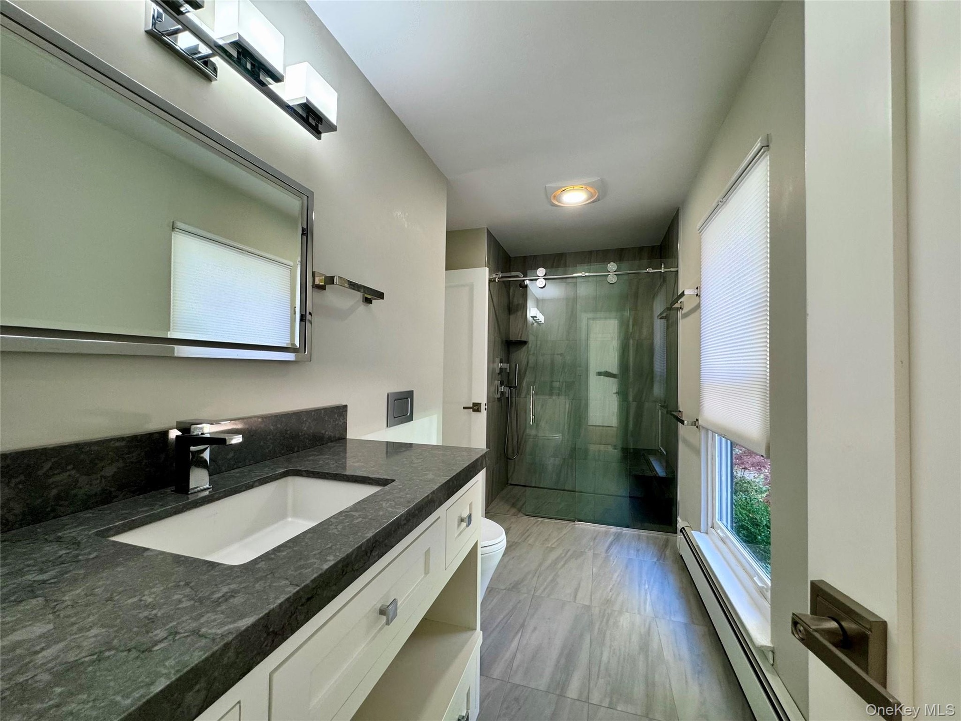 Full bath featuring a baseboard heating unit, vanity, and a stall shower