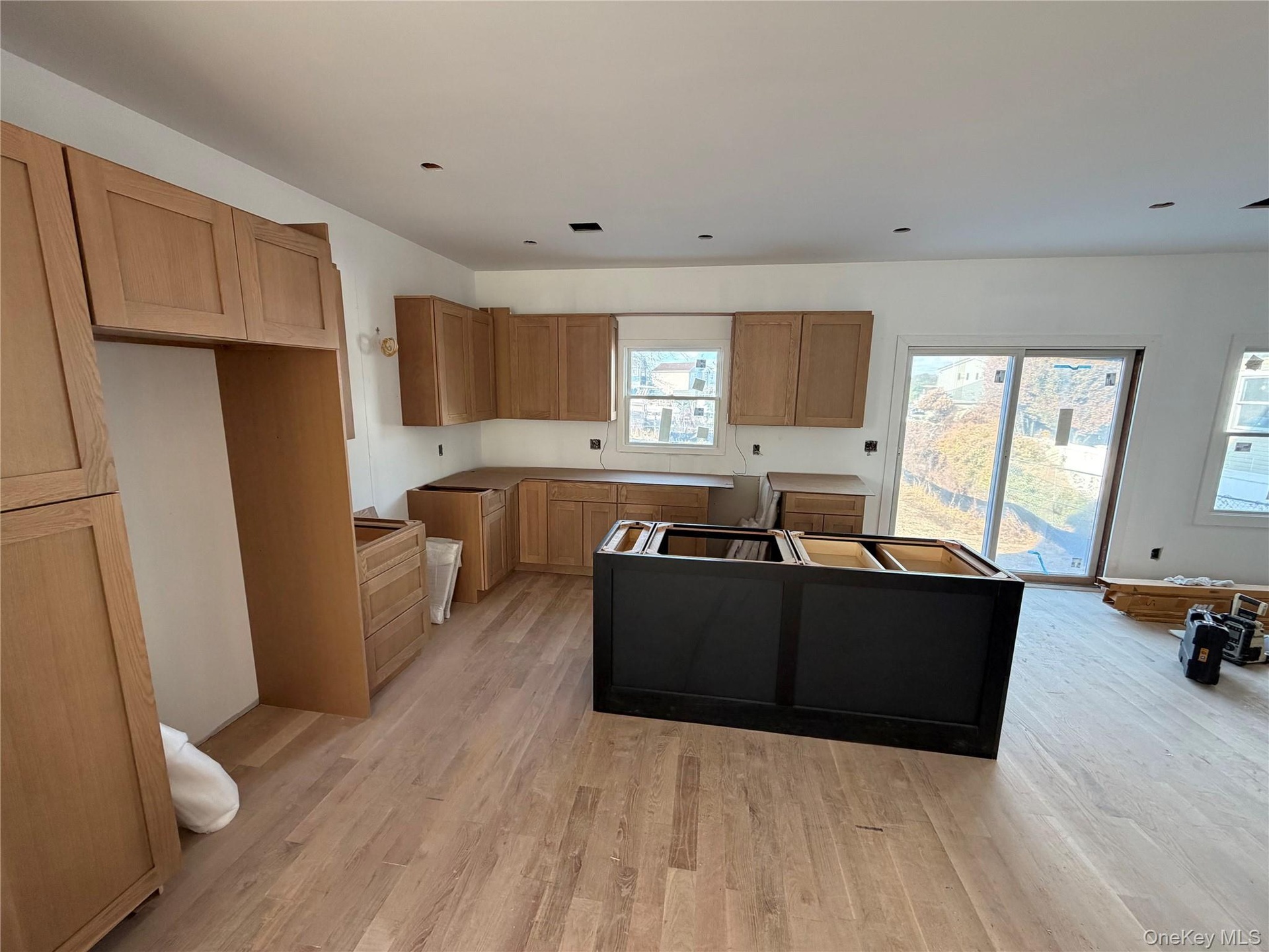 Kitchen featuring brown cabinets, a center island, light wood-style flooring, and dark cabinets