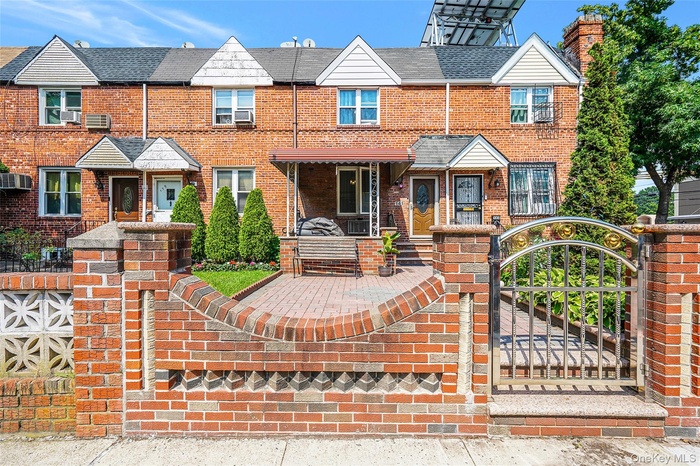 Townhome / multi-family property with brick siding and a gate