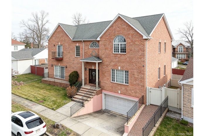 View of front of house with a gate, brick siding, a garage, and a shingled roof