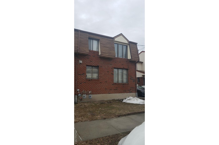 View of property exterior with mansard roof and brick siding