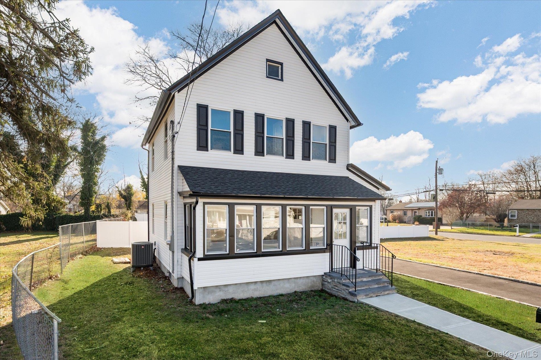 View of front of home with a sunroom and a shingled roof