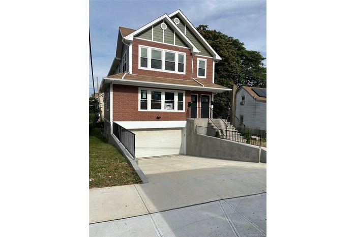 View of front facade with brick siding, driveway, a garage, and covered porch