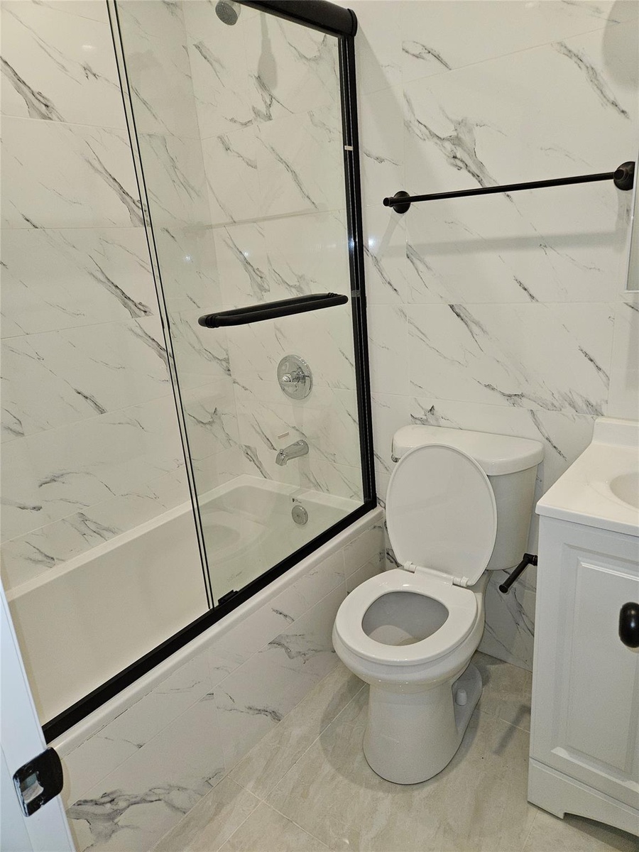 Full bathroom featuring vanity, shower / bath combination, tile walls, toilet, and marble finish floor