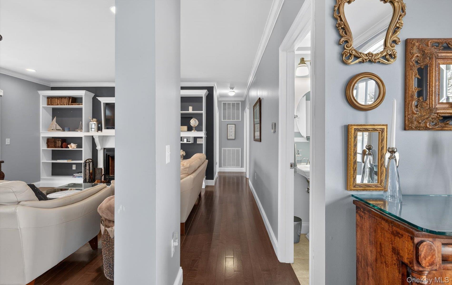 Hallway featuring dark wood finished floors, crown molding, and built in features