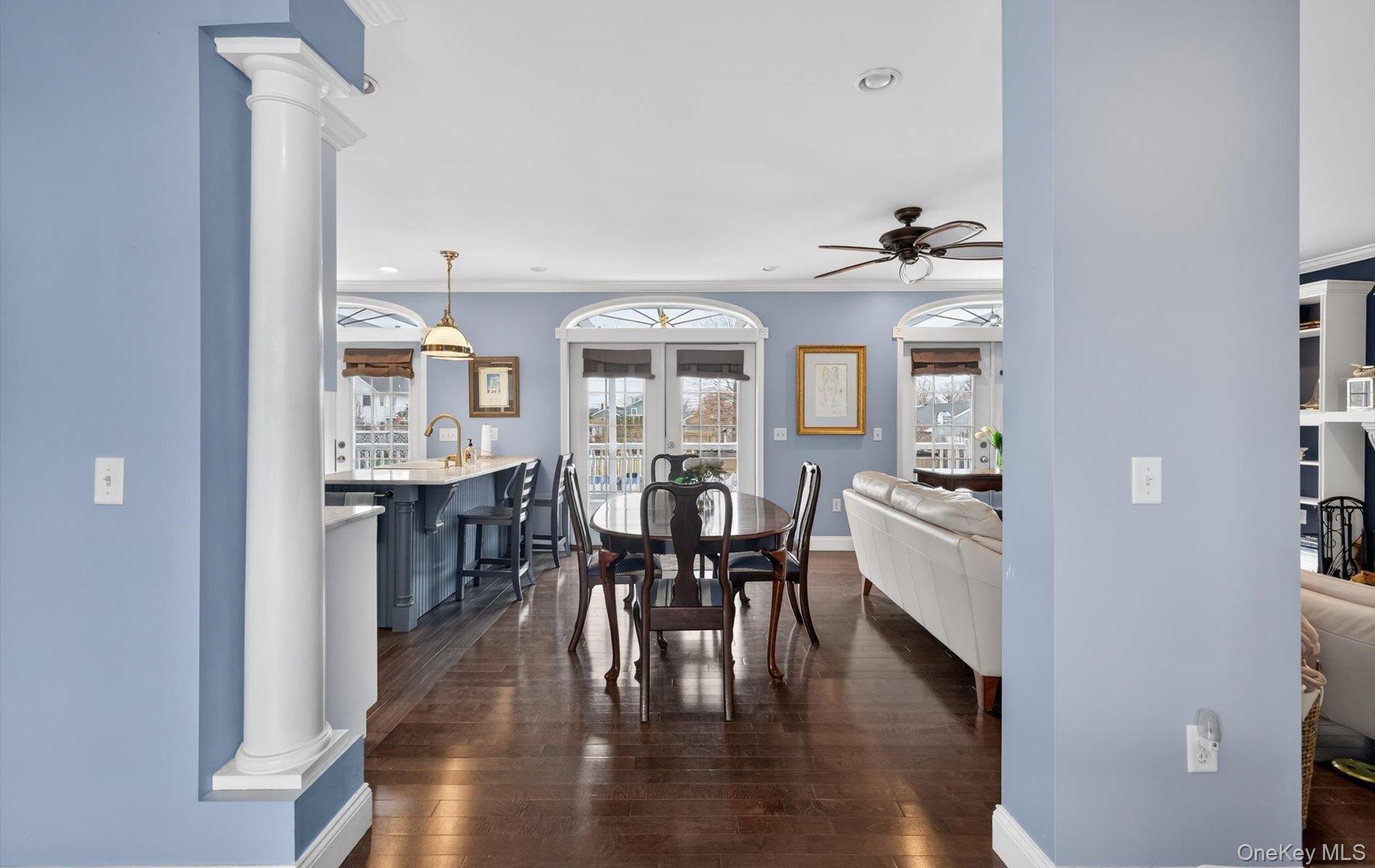 Dining space featuring decorative columns, dark wood finished floors, ornamental molding, recessed lighting, and a ceiling fan