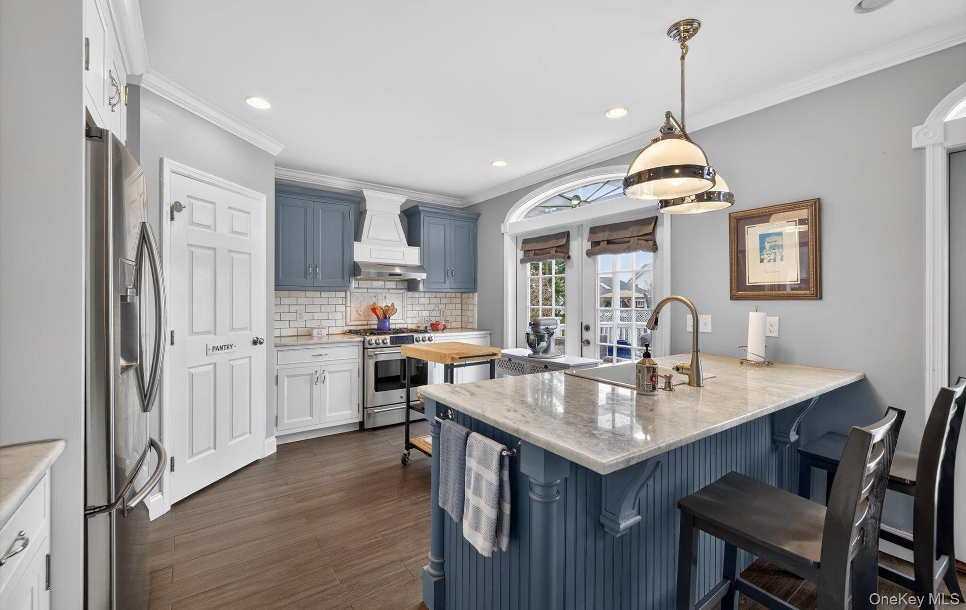 Dual tone kitchen with a breakfast bar area, a peninsula, light stone counters, stainless steel appliances, and decorative light fixtures