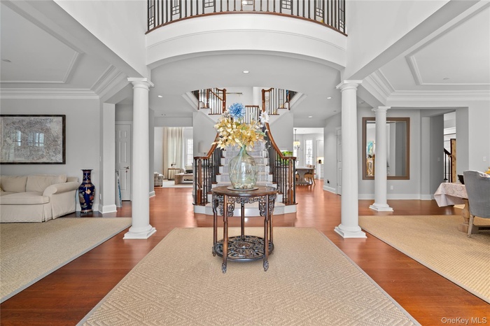 Entryway featuring ornate columns, plenty of natural light, dark wood-style floors, recessed lighting, and a high ceiling