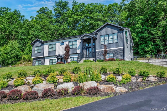 Split foyer home featuring stone siding and view of wooded area