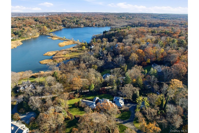 Aerial View of this special property location featuring Mill Neck Bay and a heavily wooded area