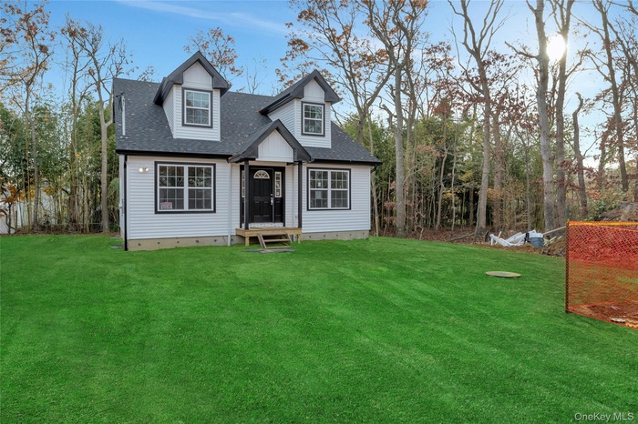 Cape cod-style house featuring a shingled roof and a front lawn