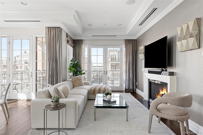 Living area featuring visible vents, ornamental molding, a lit fireplace, hardwood / wood-style flooring, and french doors