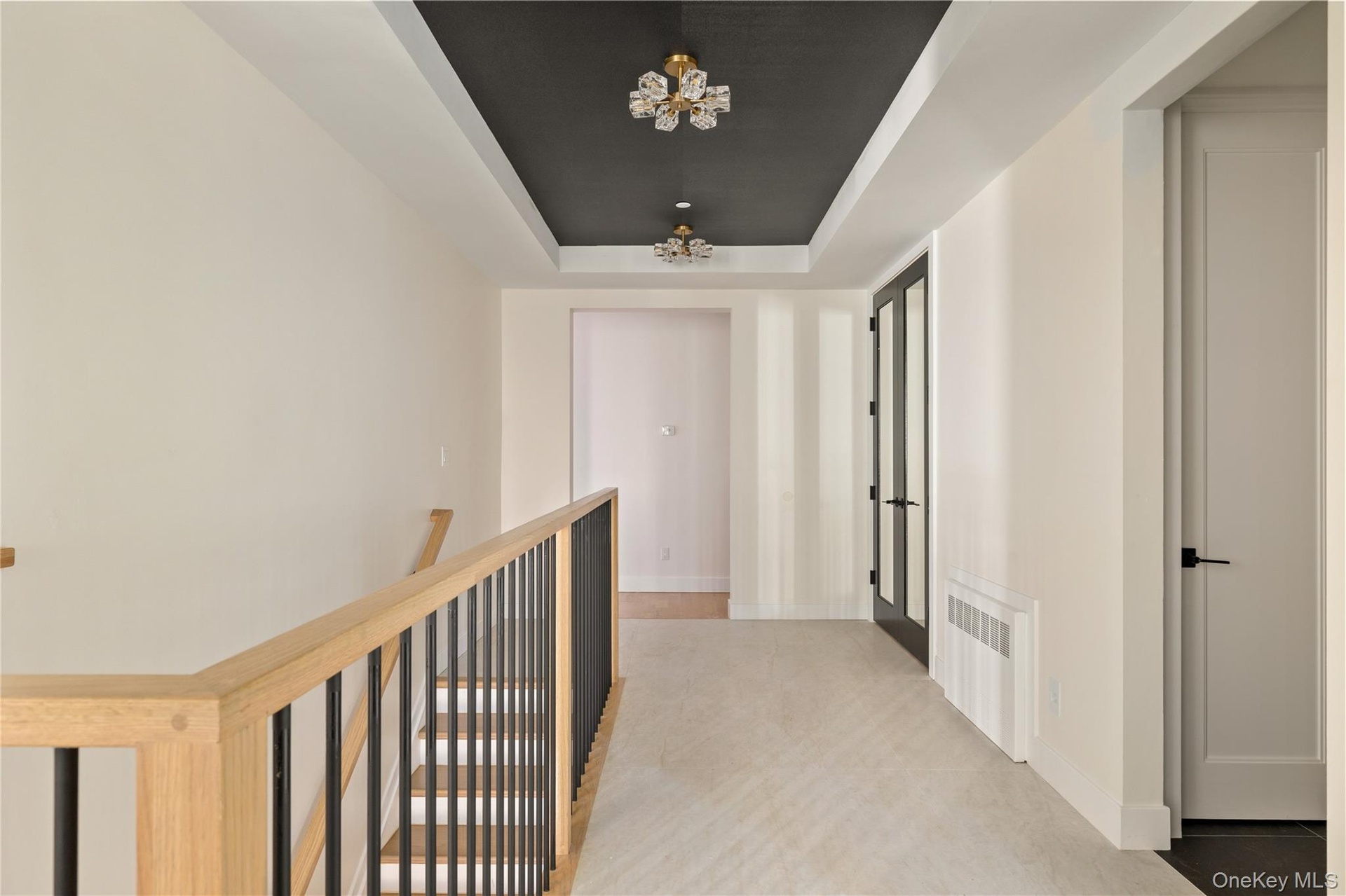 Hallway with a raised ceiling, a chandelier, and radiator