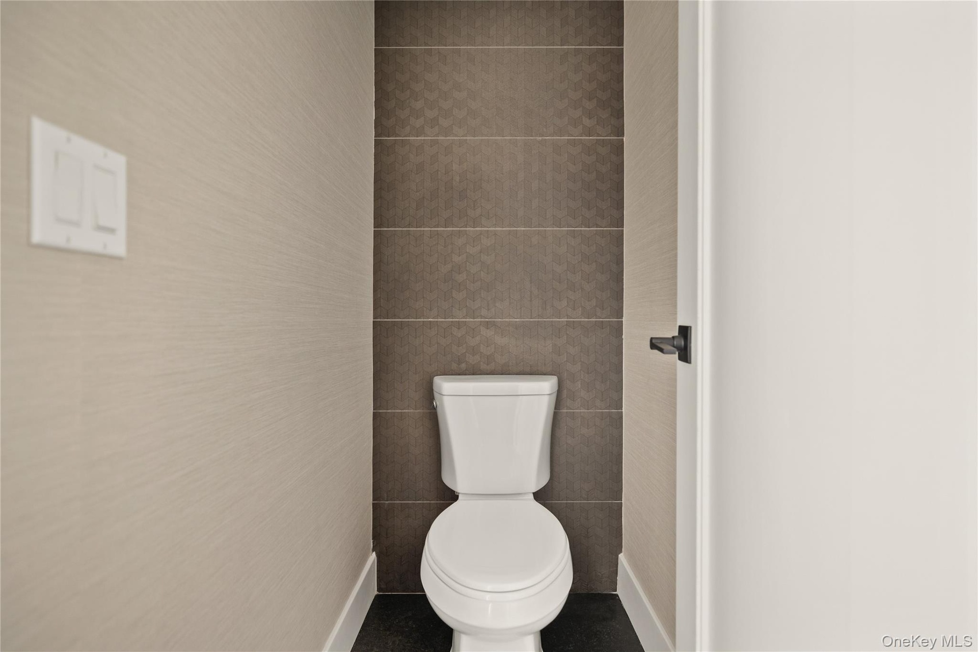 Bathroom with toilet and tile walls