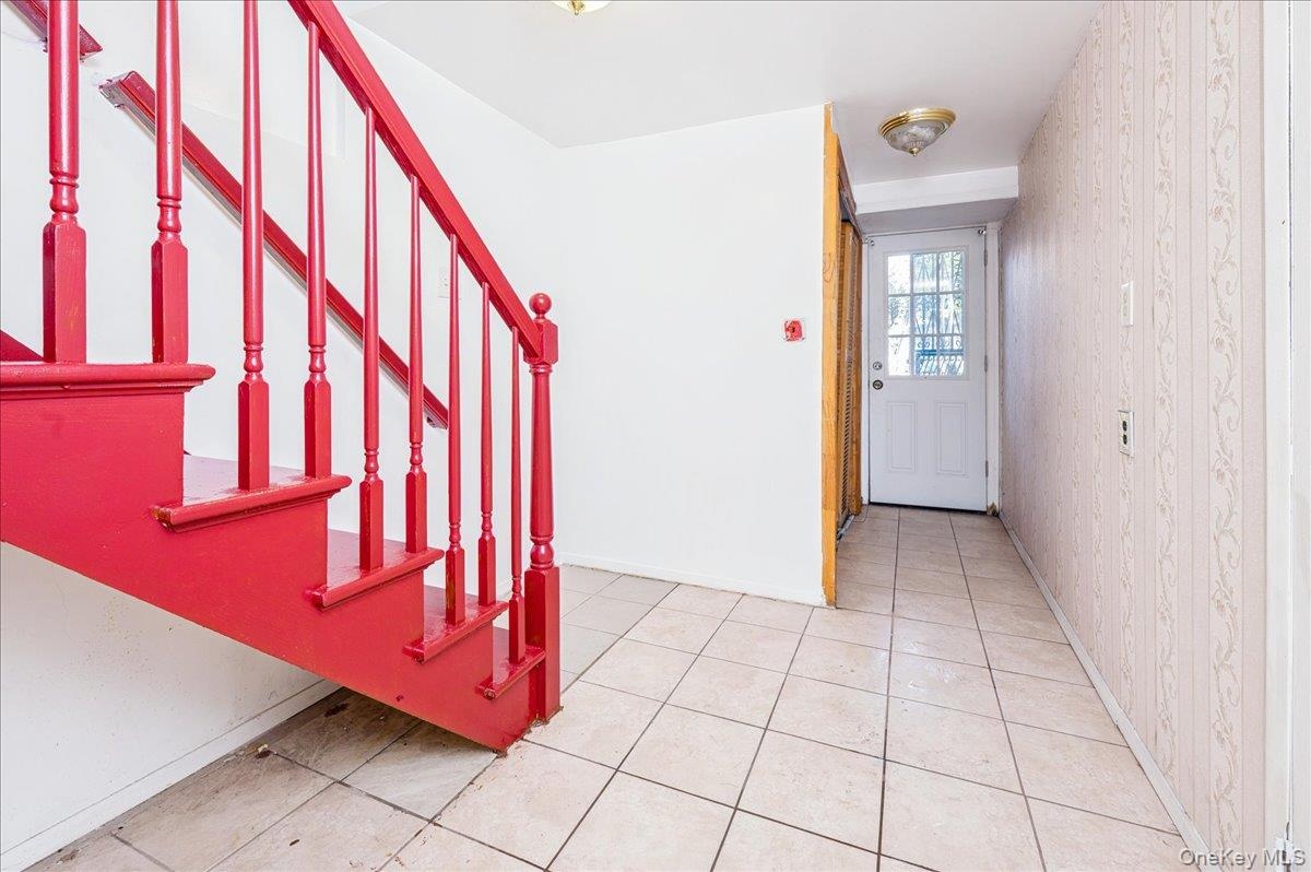 Entrance foyer with light tile patterned floors and wallpapered walls; first floorexit to backyard