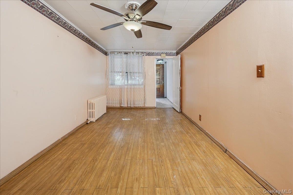 Family room featuring light wood-type flooring, radiator, a ceiling fan, and crown molding