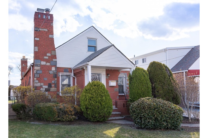 View of front of house with brick siding and a chimney