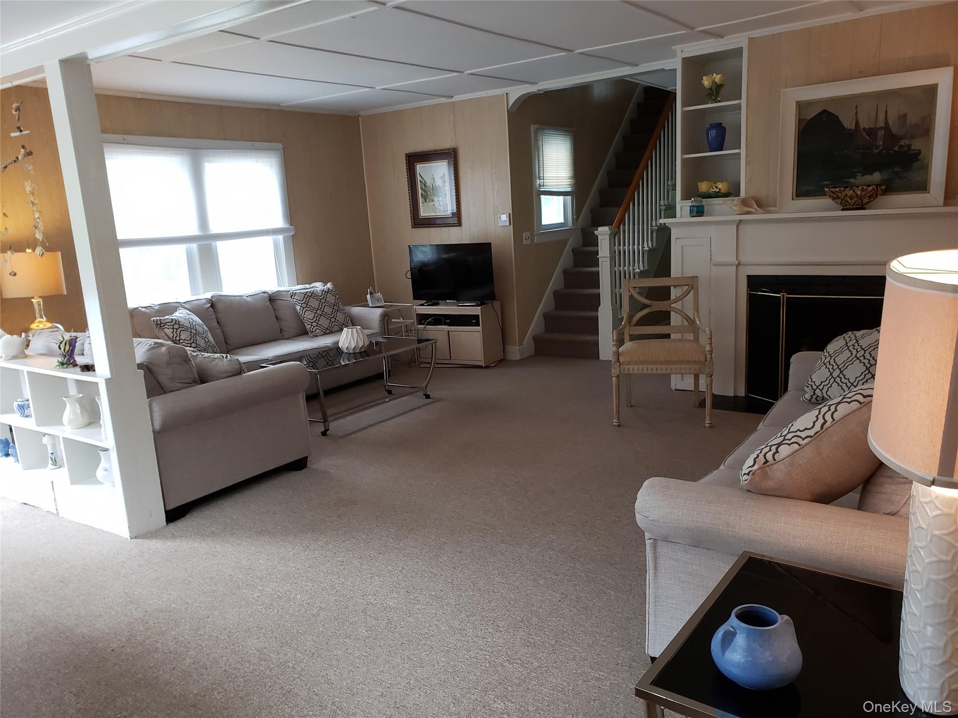 Carpeted living room with stairway, built in shelves, and a fireplace