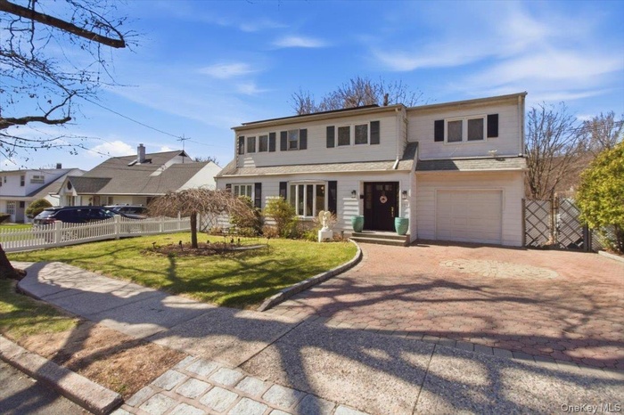 Traditional-style house featuring decorative driveway and a garage