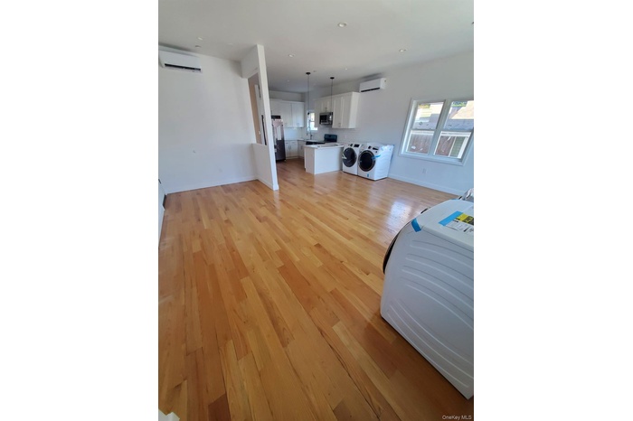Living area featuring a wall mounted air conditioner, light wood-style floors, baseboards, and recessed lighting