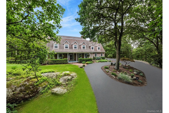 Cape cod-style house with a porch, a front lawn, and curved driveway