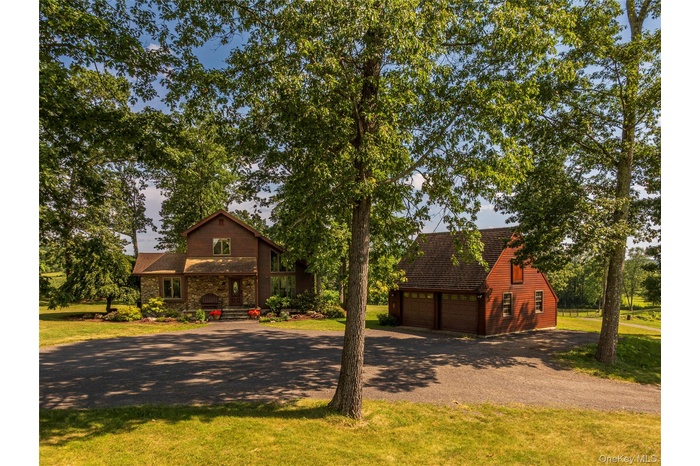 View of front of home featuring driveway, a garage, an outbuilding, and a front lawn
