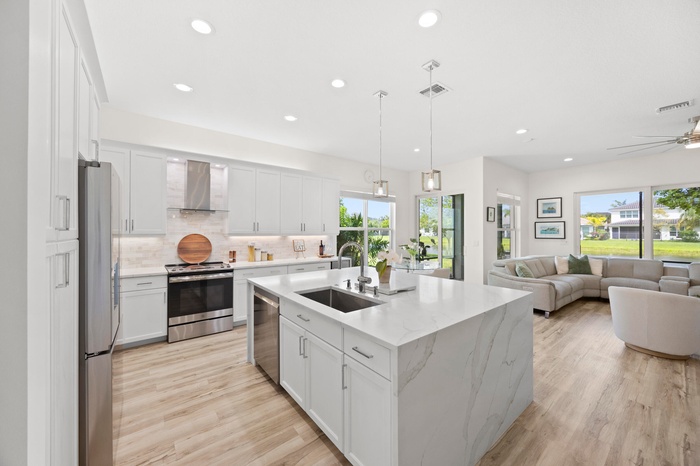 Open concept floor plan, with white shaker cabinets and Calacatta gold quartz tops and expanded kitchen island.