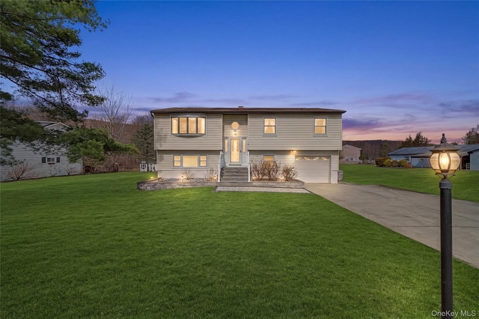 Raised ranch with a lawn, driveway, and an attached garage