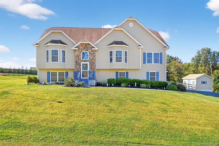 Bi-level home featuring a front lawn and stone siding