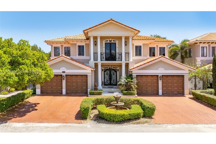 A grand Mediterranean-style estate at sunset, with a terracotta tile roof, ornate double entry doors, lion statues, Corinthian columns, a Juliet balco