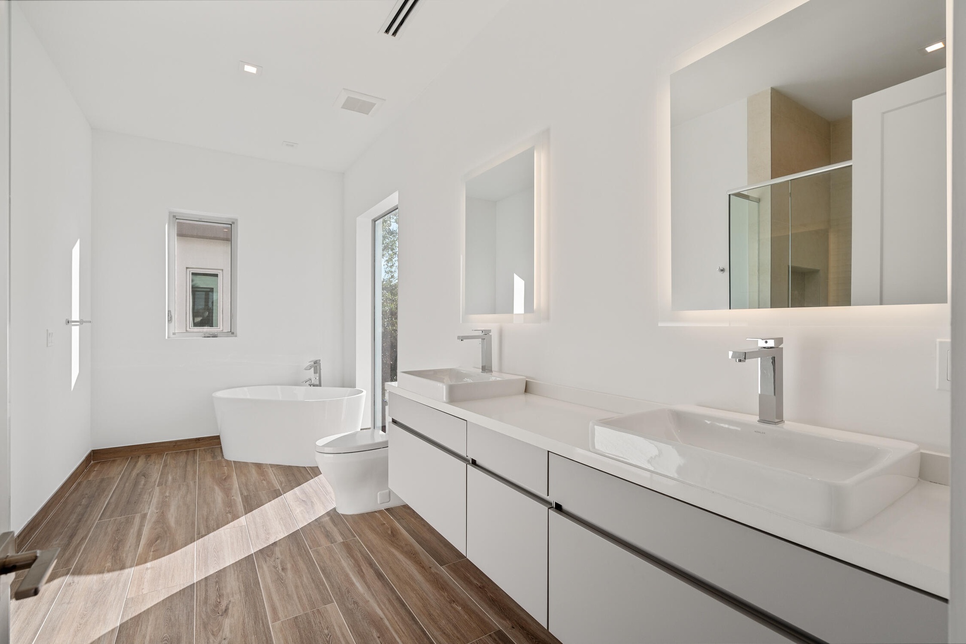 Spacious primary bathroom with dual sinks, ample storage and spa-style soaking tub.