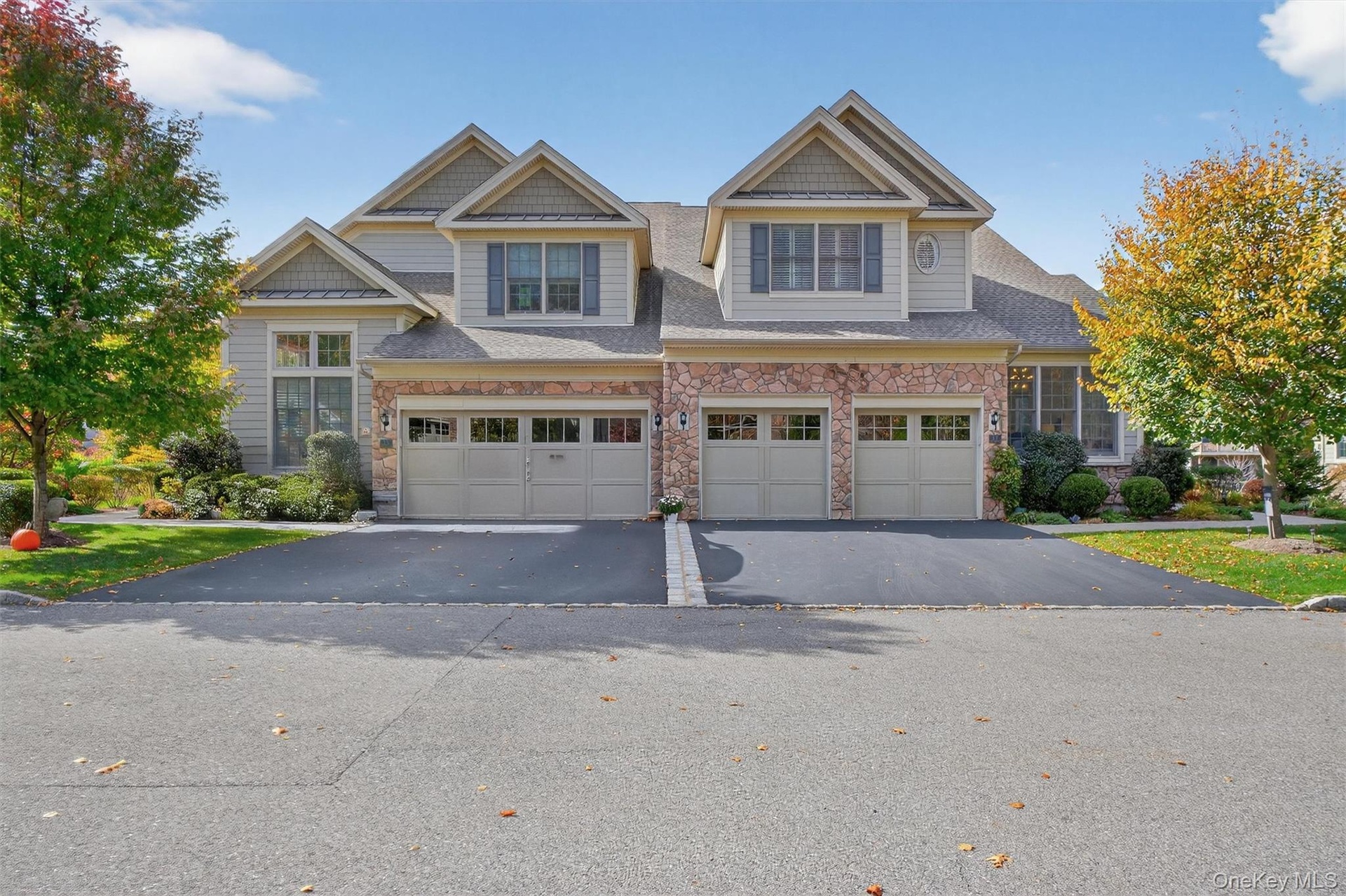 Craftsman house with stone siding, driveway, an attached garage, and a shingled roof