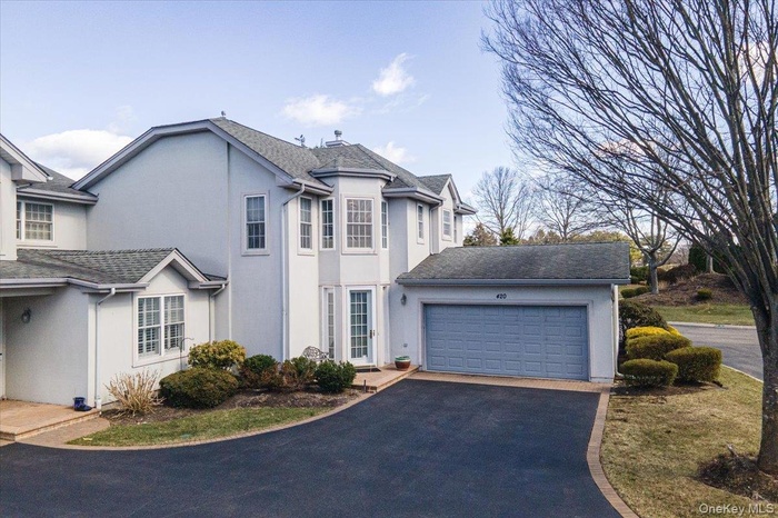 View of front of home featuring an attached garage, stucco siding, driveway, and roof with shingles