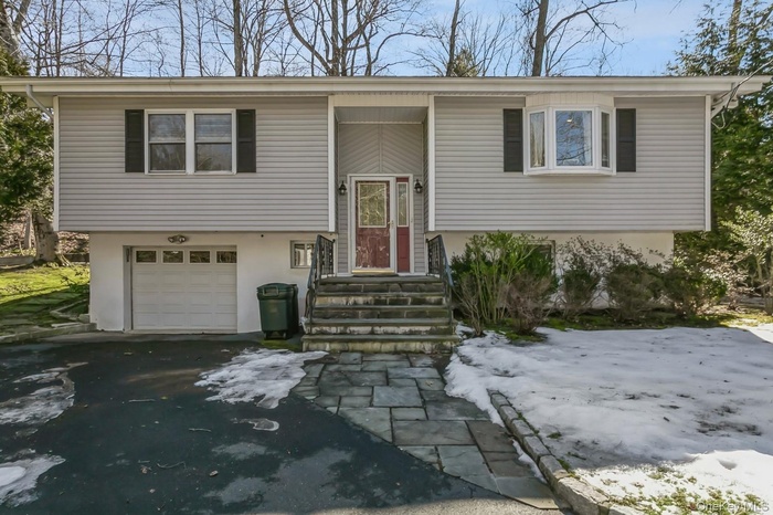 Bi-level home featuring an attached garage, aphalt driveway, and stucco siding