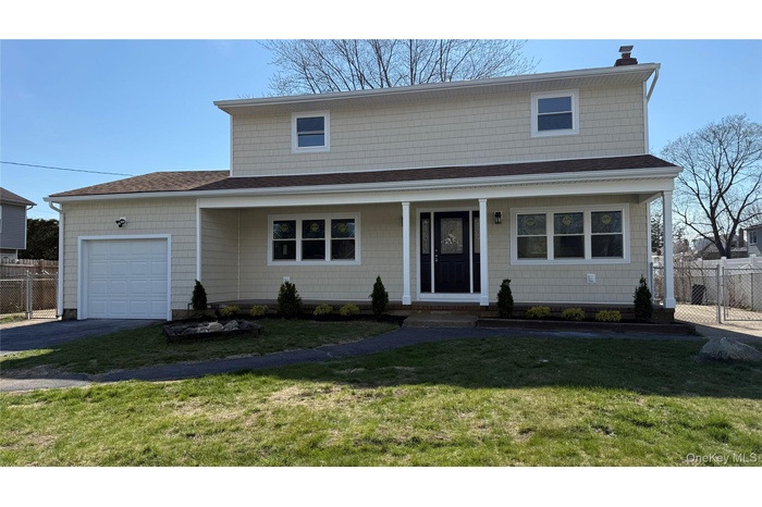 WELCOME HOME!Front facade with a covered porch, an attached one car garage, chimney, asphalt driveway, and chain link fence