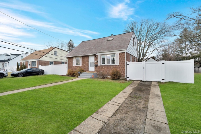 Bungalow-style home with a gate, a shingled roof, and brick siding