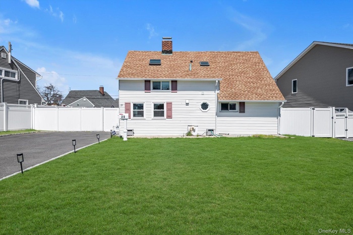 Back of house featuring a chimney, a shingled roof, and a fenced backyard