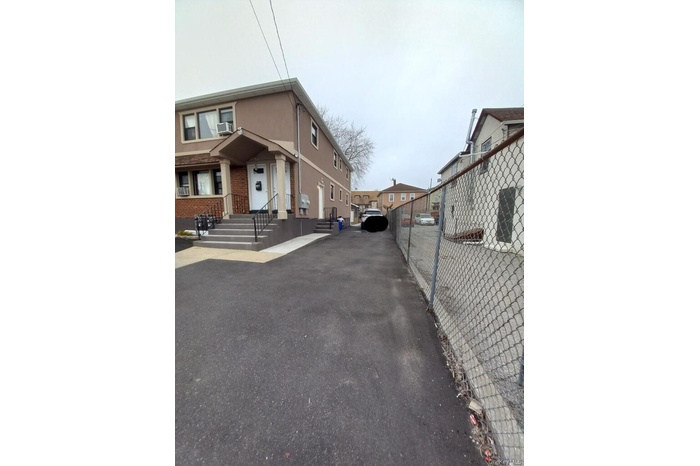 The property features a paved driveway and a two-story exterior with a porch entrance
