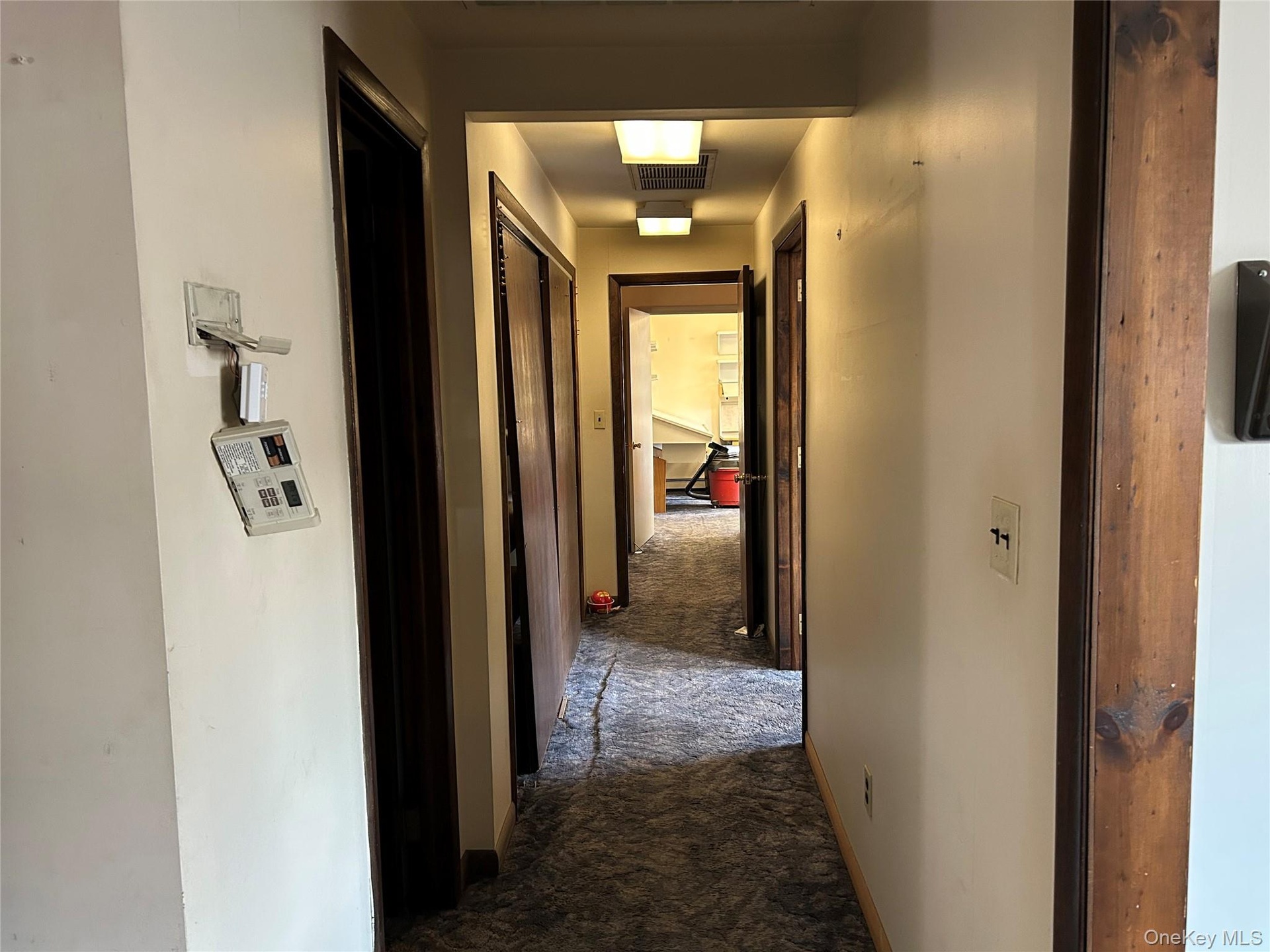 Corridor featuring dark carpet and baseboards