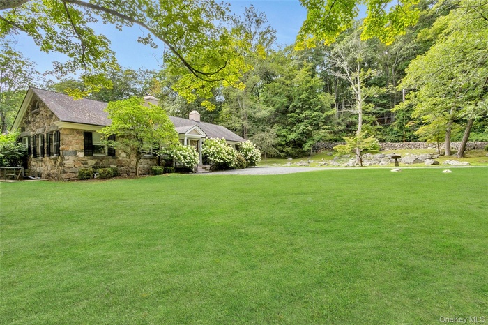 Front of home, with manicured lawn, stone walls and rock garden