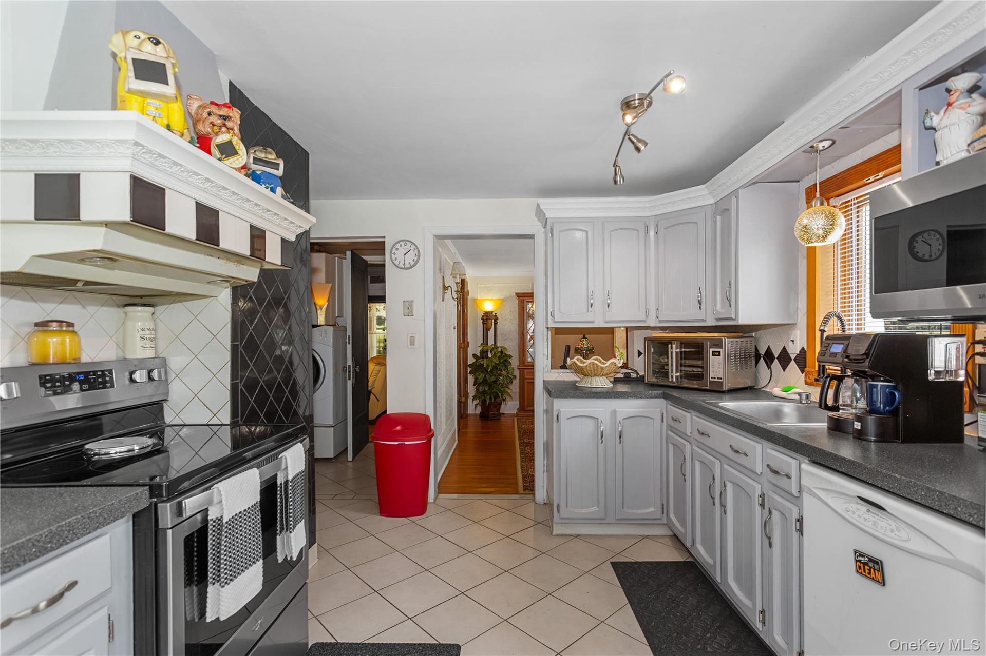 Kitchen featuring, dark countertops, backsplash, light tile patterned flooring, and healthy amount of natural light