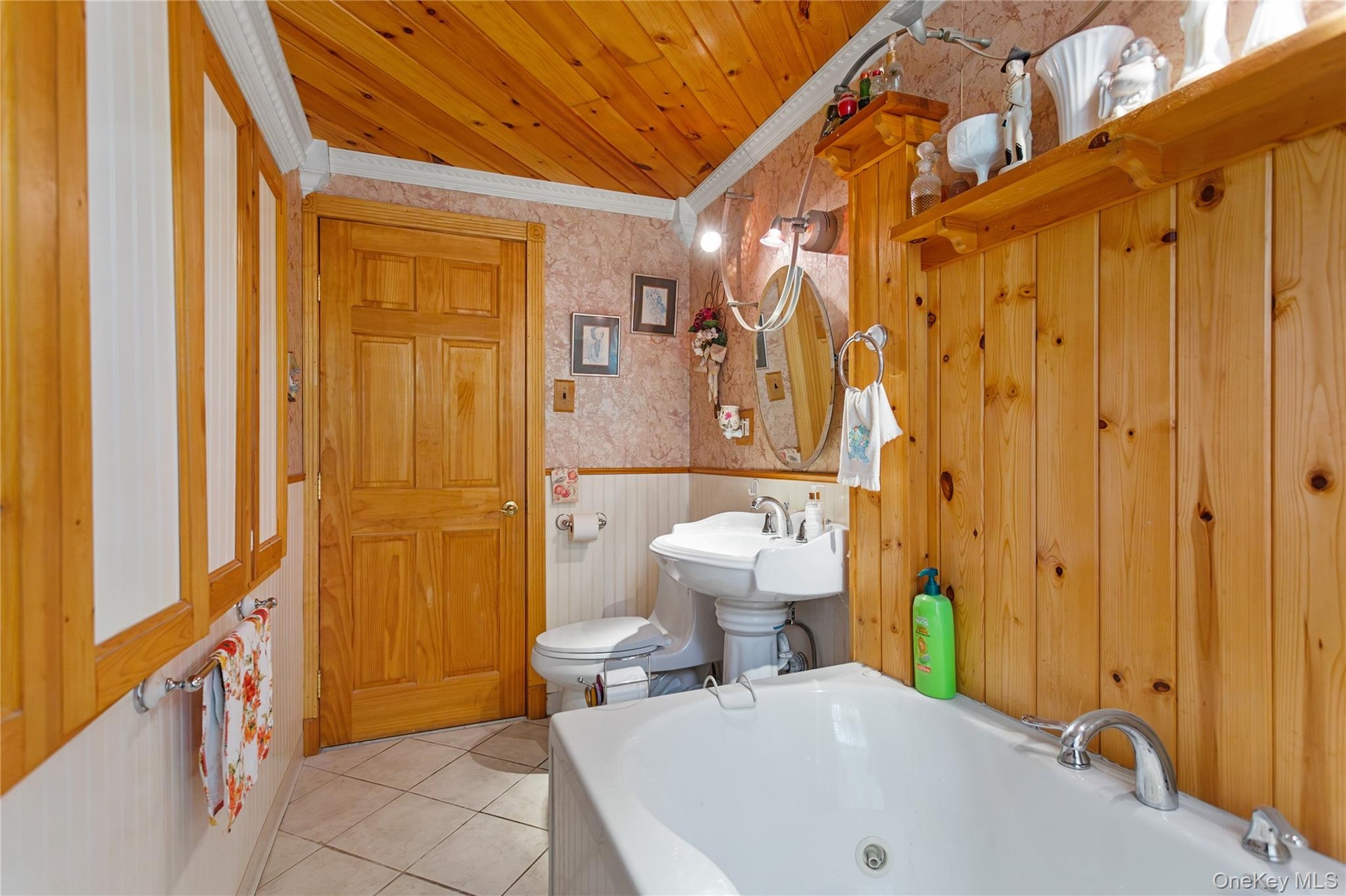 Bathroom featuring wallpapered walls, wainscoting, a whirlpool tub, tile patterned floors, and ornamental molding