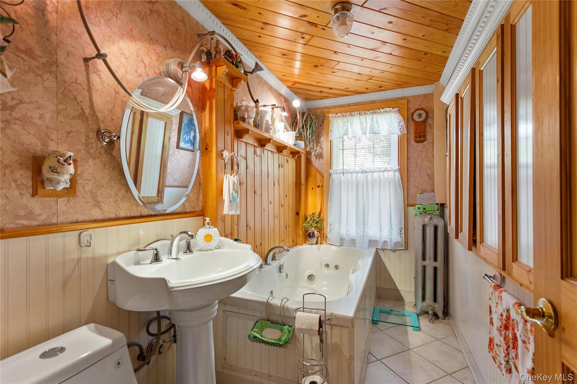 Bathroom featuring wallpapered walls, a whirlpool tub, wooden ceiling, a wainscoted wall, and wooden walls