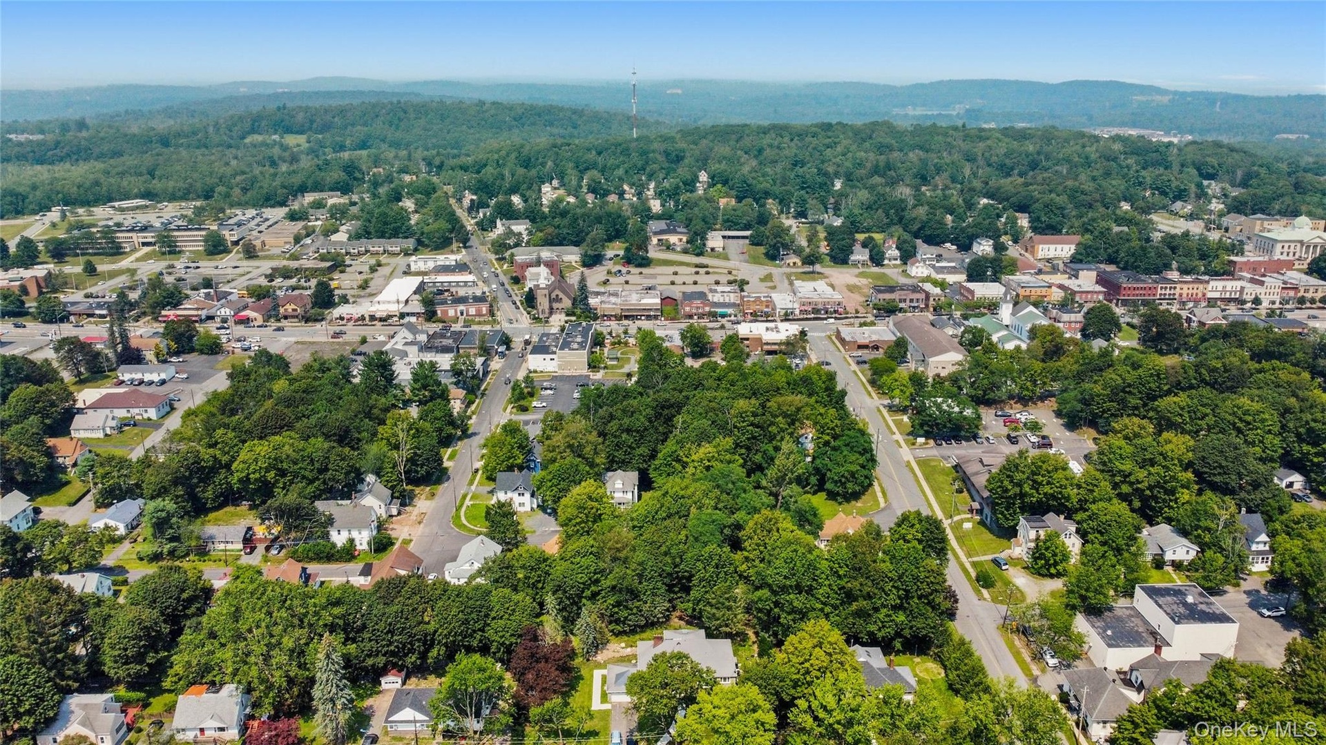 Aerial view of property and surrounding area featuring nearby suburban area and mountains