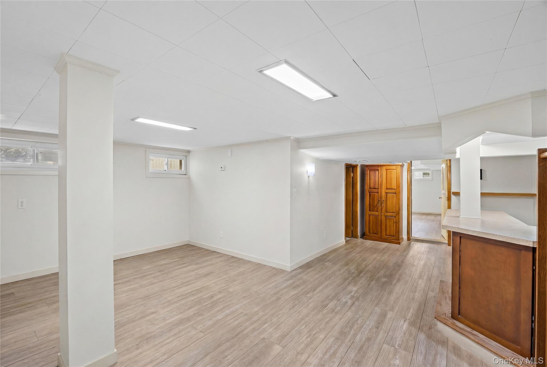 This expansive room features light-toned flooring, white walls, and a white ceiling with recessed lighting
