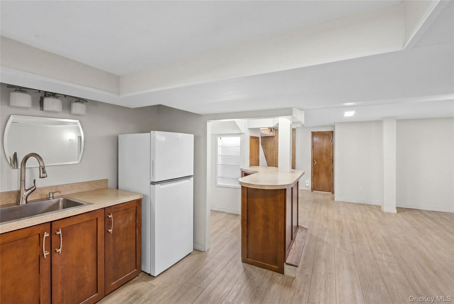 This expansive space features light wood-look flooring, a wet bar with a curved countertop.