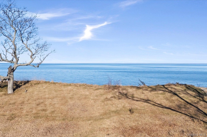 Peaceful bluff-top setting with open lawn and expansive water views, showcasing the property's scenic waterfront backdrop and wide horizon beyond.